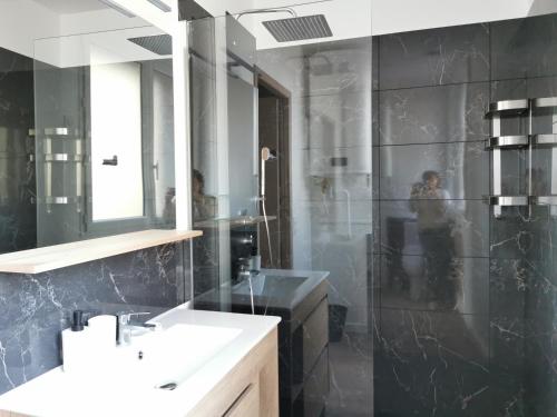 een badkamer met een douche, een wastafel en een spiegel bij Appart Hotel Cinéma Perpignan in Perpignan