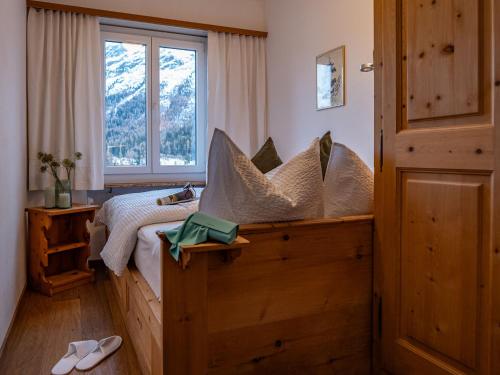 ein Schlafzimmer mit einem Bett mit Kissen und einem Fenster in der Unterkunft Apartment Chesa Sonnalpine B 55 by Interhome in St. Moritz