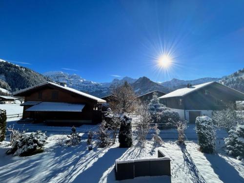 a house covered in snow with the sun in the background at Apartment Chalet Ilge by Interhome in Lenk