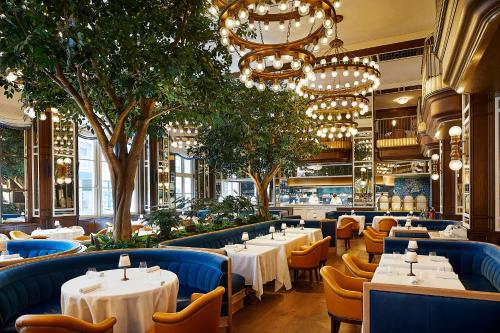 a restaurant with white tables and chairs and trees at The Fifth Avenue Hotel in New York
