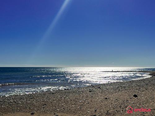a beach with the sun reflecting on the water at Marina Sunset 1era línea in Oropesa del Mar