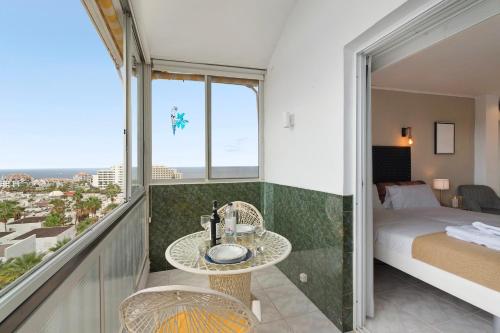 a bedroom with a balcony with a bed and a table at Apto El Dorado 929 in Playa de las Americas