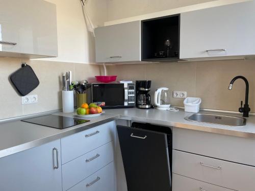 uma cozinha com armários brancos e um micro-ondas preto em Apartment Haus Stefanie by Interhome em Trinwillershagen