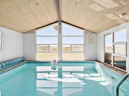 een zwembad met blauw water in een kamer met ramen bij Holiday Home Månviva - 500m from the sea in NW Jutland by Interhome in Løkken