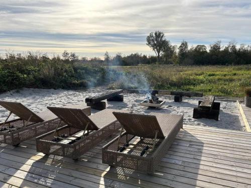 a wooden deck with chairs and a fire pit at Holiday Home Grep - 800m from the sea in NE Jutland by Interhome in Strandby