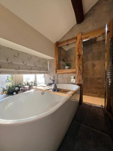 uma grande banheira branca na casa de banho com chuveiro em The Fleece Inn at Barkisland em Ripponden