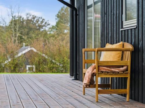 une chaise en bois assise sur la terrasse couverte d'une maison dans l'établissement Holiday Home Francis - all inclusive - 380m from the sea by Interhome, à Frørup