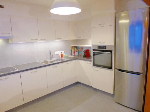 een keuken met witte kasten en een roestvrijstalen koelkast bij Apartment Maze B by Interhome in Chermignon-dʼen Haut
