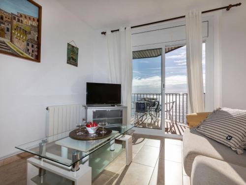 uma sala de estar com uma mesa de vidro e uma televisão em Apartment Calima by Interhome em Sant Antoni de Calonge