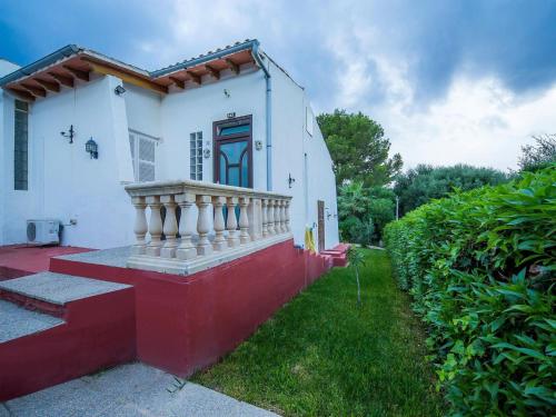a small white and red house with a porch at Holiday Home Bonita by Interhome in Cala Anguila