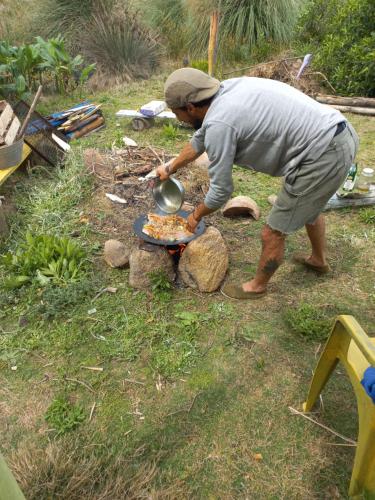 a man cooking food on a plate on a grill at Ajo Aloha Hostel in Cabo Polonio