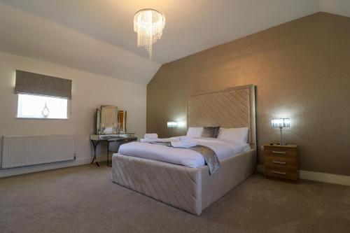 a bedroom with a large bed and a chandelier at Northumberland Luxury Stays - The Newland in West Chevington