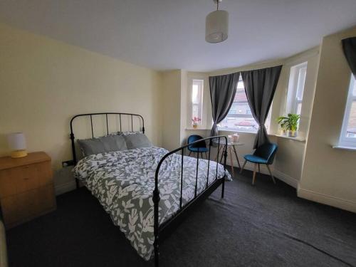 ロンドンにあるCozy place to stay in Londonのベッドルーム1室(ベッド1台、テーブル、窓2つ付)