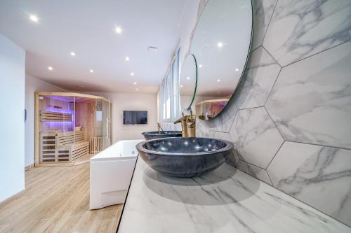 a bathroom with two sinks and a large mirror at L'Evasion - Sauna Jacuzzi Cinema in Tours