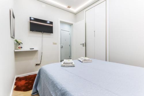 een witte kamer met een bed en een flatscreen-tv bij Vita Portucale ! Moscavide Casa Branca w/ Terrace in Lissabon
