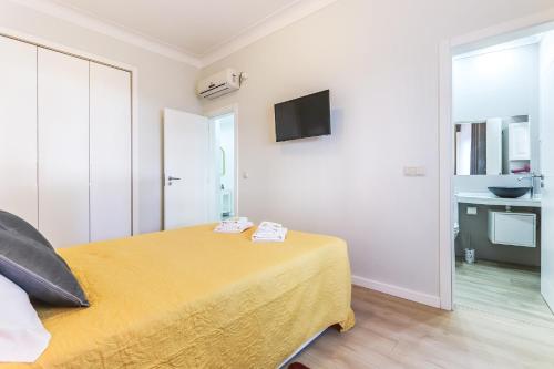 a bedroom with a yellow bed and a television at Vita Portucale ! Moscavide Casa Branca w/ Terrace in Lisbon