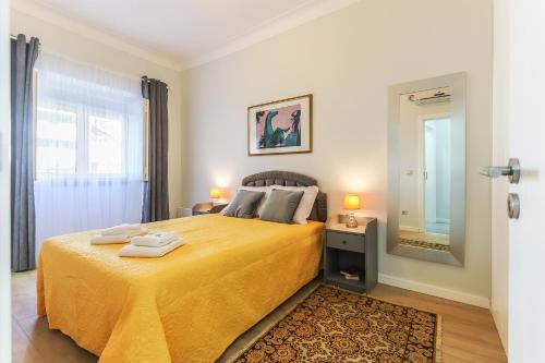 een slaapkamer met een groot geel bed en een spiegel bij Vita Portucale ! Moscavide Casa Branca w/ Terrace in Lissabon