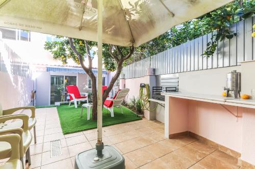 an umbrella on a patio with a table and chairs at Vita Portucale ! Moscavide Casa Branca w/ Terrace in Lisbon