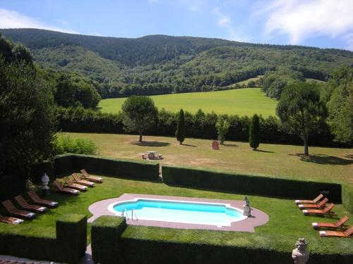 a swimming pool in the middle of a lawn with chairs at Demeure de Flore in Lacabarède