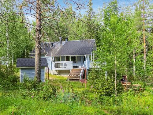 a blue house with a porch and stairs in the woods at Holiday Home Ukkorinne mökki by Interhome in Hyrynsalmi