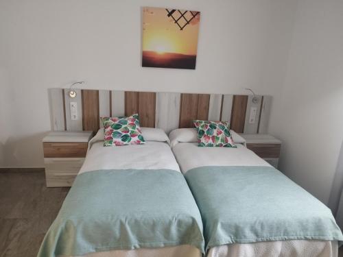 2 camas en una habitación con una foto en la pared en Hotel El Duende en Madridejos