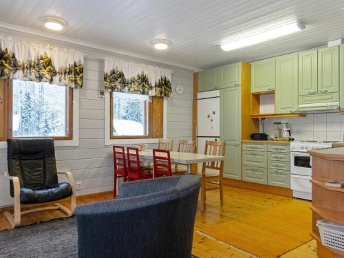 una cocina con armarios verdes, mesa y sillas en Holiday Home Käpälämäki by Interhome en Raanujärvi