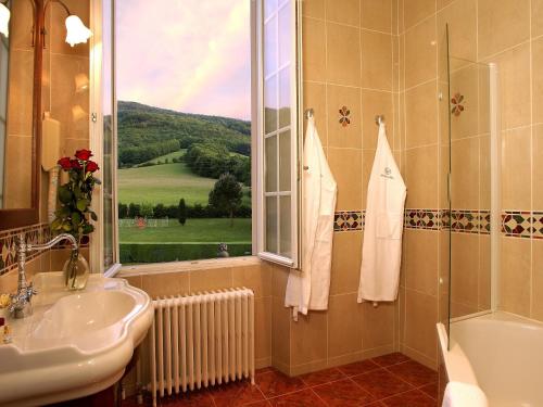 La salle de bains est pourvue d'un lavabo, d'une fenêtre et d'une baignoire. dans l'établissement Demeure de Flore, à Lacabarède