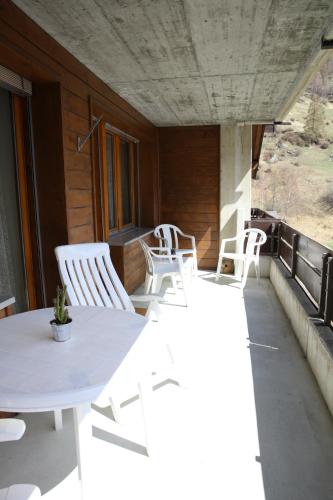 a white table and white chairs on a balcony at Monte Rosa Apartments Täsch in Täsch