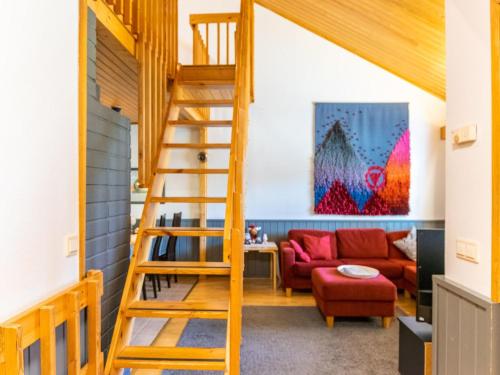 a wooden staircase in a living room with a red couch at Holiday Home Teerenpesue e 38 by Interhome in Saariselka