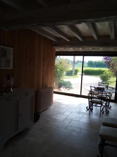 une pièce avec une table et des chaises et une grande fenêtre dans l'établissement Ferme de la NOE, à Sérigny