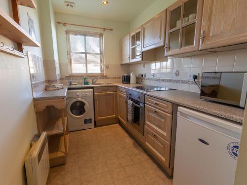 kuchnia z drewnianymi szafkami, pralką i suszarką w obiekcie Apartment Millar House by Interhome w mieście Inverness