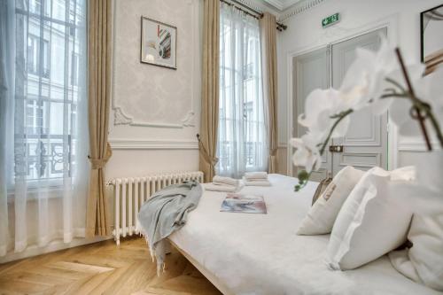 une chambre blanche avec un grand lit avec des oreillers blancs dans l'établissement Galeries LaFayette - 7 bedrooms - lift - aircon, à Paris