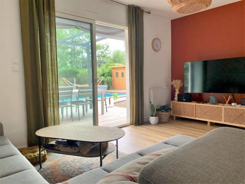 ein Wohnzimmer mit einem Sofa, einem TV und einem Tisch in der Unterkunft Villa Le Faré by Interhome in Azur