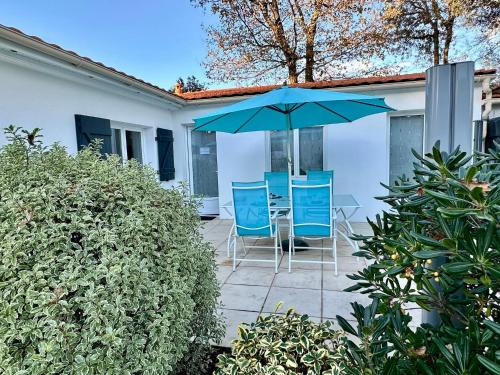 un patio con sillas azules y una sombrilla en Holiday Home Joannie by Interhome, en Saint-Brevin-les-Pins