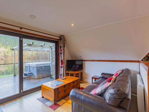 a living room with a leather couch and a television at Chalet Lodge 26 by Interhome in Spean Bridge
