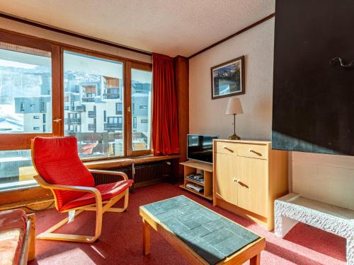 un salon avec une chaise rouge et une télévision dans l'établissement Apartment Le Grand Tichot A et B - Val Claret-17 by Interhome, à Tignes