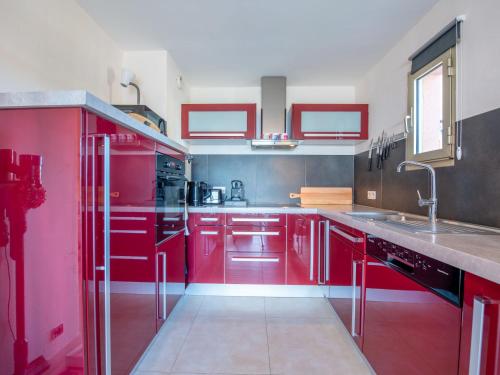 une cuisine rouge avec des appareils en acier inoxydable et des armoires rouges dans l'établissement Apartment La Croix du Sud-28 by Interhome, à Cavalaire-sur-Mer