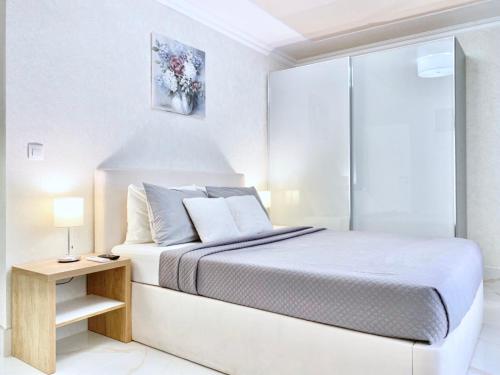een witte slaapkamer met een bed en een tafel bij Sea View Apartment with Free Parking in Pomorie