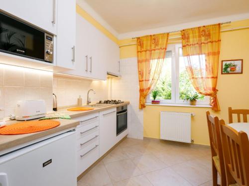 una cucina con armadi bianchi, tavolo e finestra di Apartment Alice by Interhome a Balatonföldvár