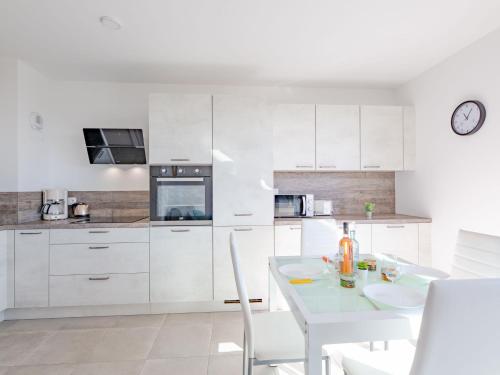 une cuisine avec des placards blancs et une table et des chaises blanches dans l'établissement Apartment Le Diamanti-2 by Interhome, à Saint-Aygulf