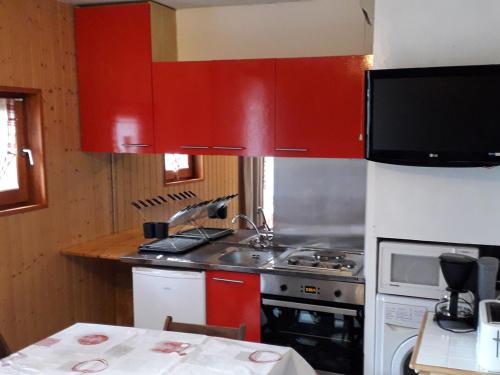 La cuisine est équipée de placards rouges et d'un four avec plaques de cuisson. dans l'établissement **Studio Cabine pour 4 pers. - Confort, Proximité Commerces/Télécabine, Animaux Acceptés** - FR-1-263-5, à Valloire
