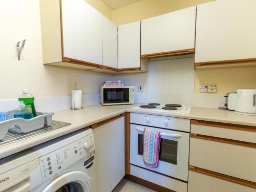 a kitchen with a washing machine and a microwave at Apartment Miller Apartment by Interhome in Inverness