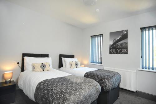 2 camas en una habitación con paredes y ventanas blancas en Refurbished House Long Stay Welcome Free Parking en Southampton