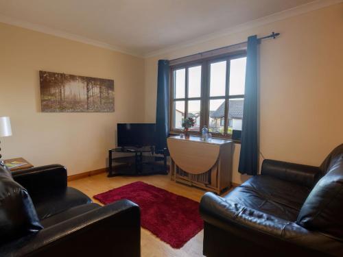 una sala de estar con 2 sillas de cuero y una ventana en Apartment Towerhill Apartment by Interhome en Inverness