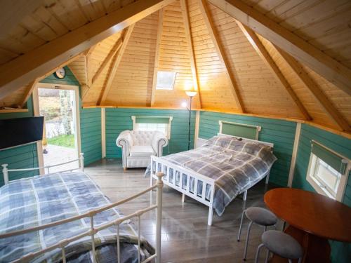 a attic bedroom with two beds and a table and chairs at Chalet Glen by Interhome in Drumnadrochit