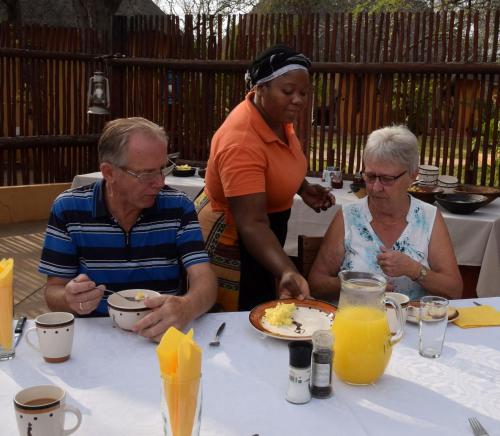 three people sitting at a table with a plate of food at Normann Safari Bush Lodge in Phalaborwa