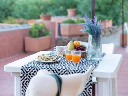 a table with a bowl of fruit and a vase of flowers at Apartment 0-5-N - Marineledda by Interhome in Golfo Aranci