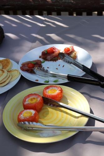 two plates of food with tomatoes and tongs on a table at Normann Safari Bush Lodge in Phalaborwa