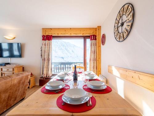 une table à manger avec une horloge sur le mur dans l'établissement Apartment Le Bec Rouge - Le Lac-10 by Interhome, à Tignes