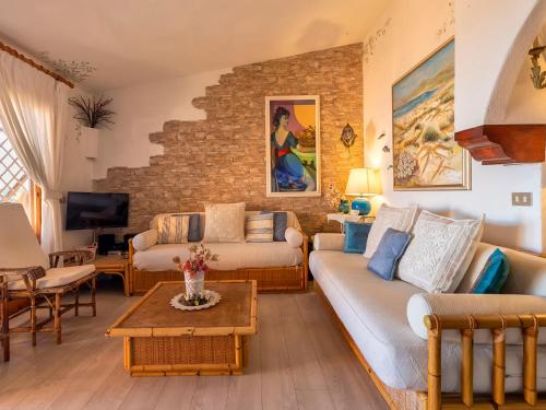 a living room with two couches and a brick wall at Apartment E-1-4 - Marineledda by Interhome in Golfo Aranci